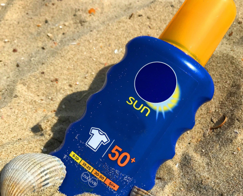photo of sunscreen bottle on the beach